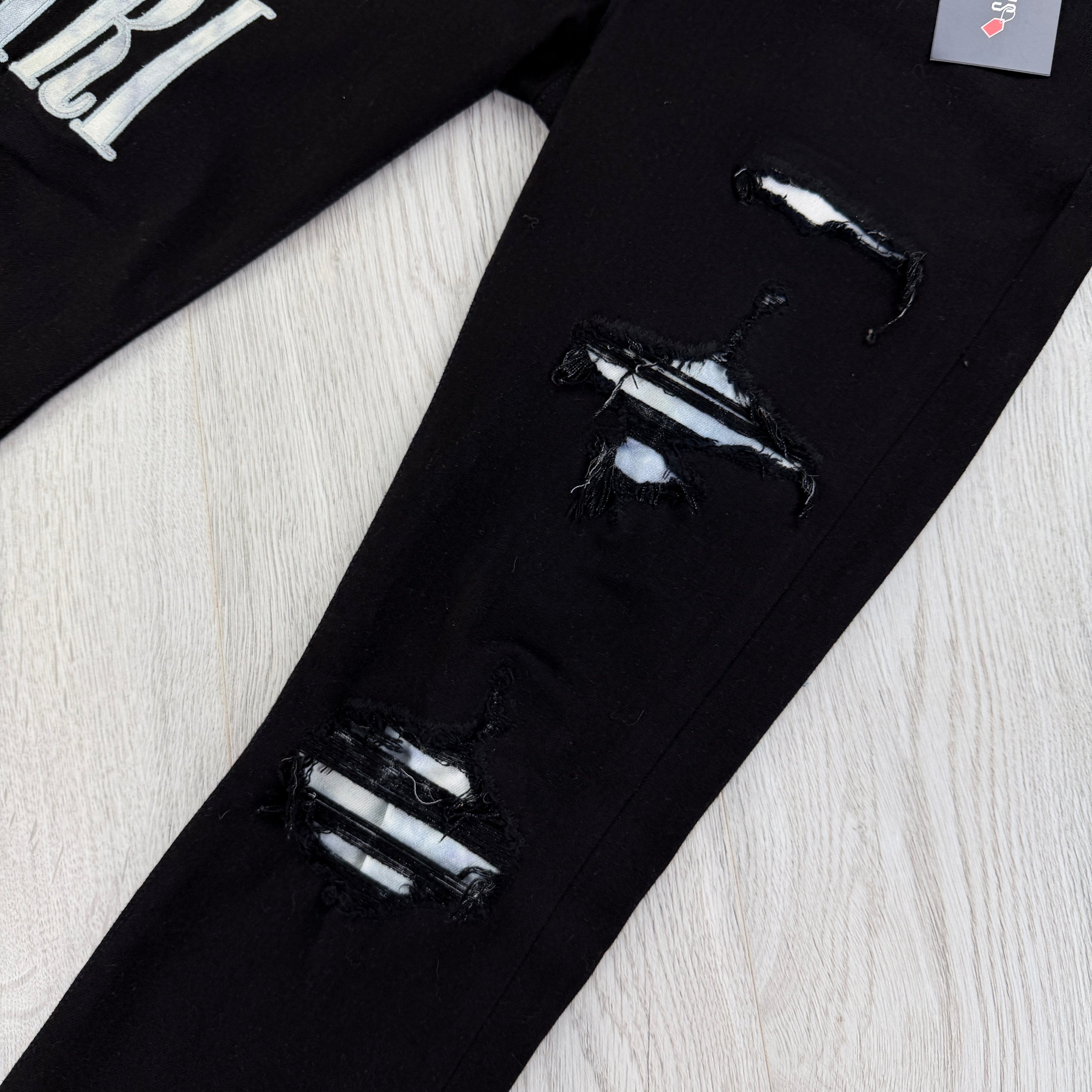 Amiri MX1 Men’s Black Distressed Jeans With Blue Side Logo