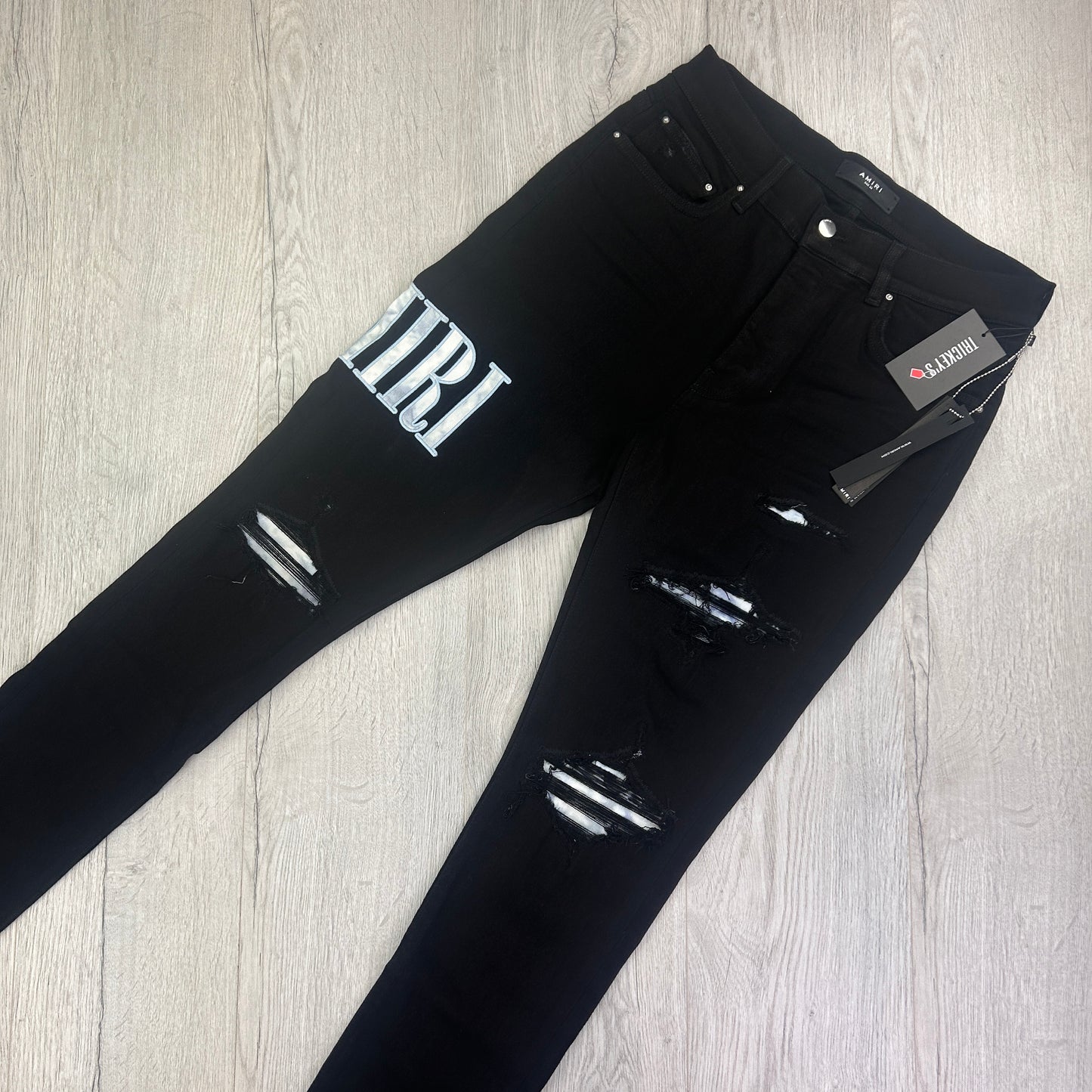 Amiri MX1 Men’s Black Distressed Jeans With Blue Side Logo