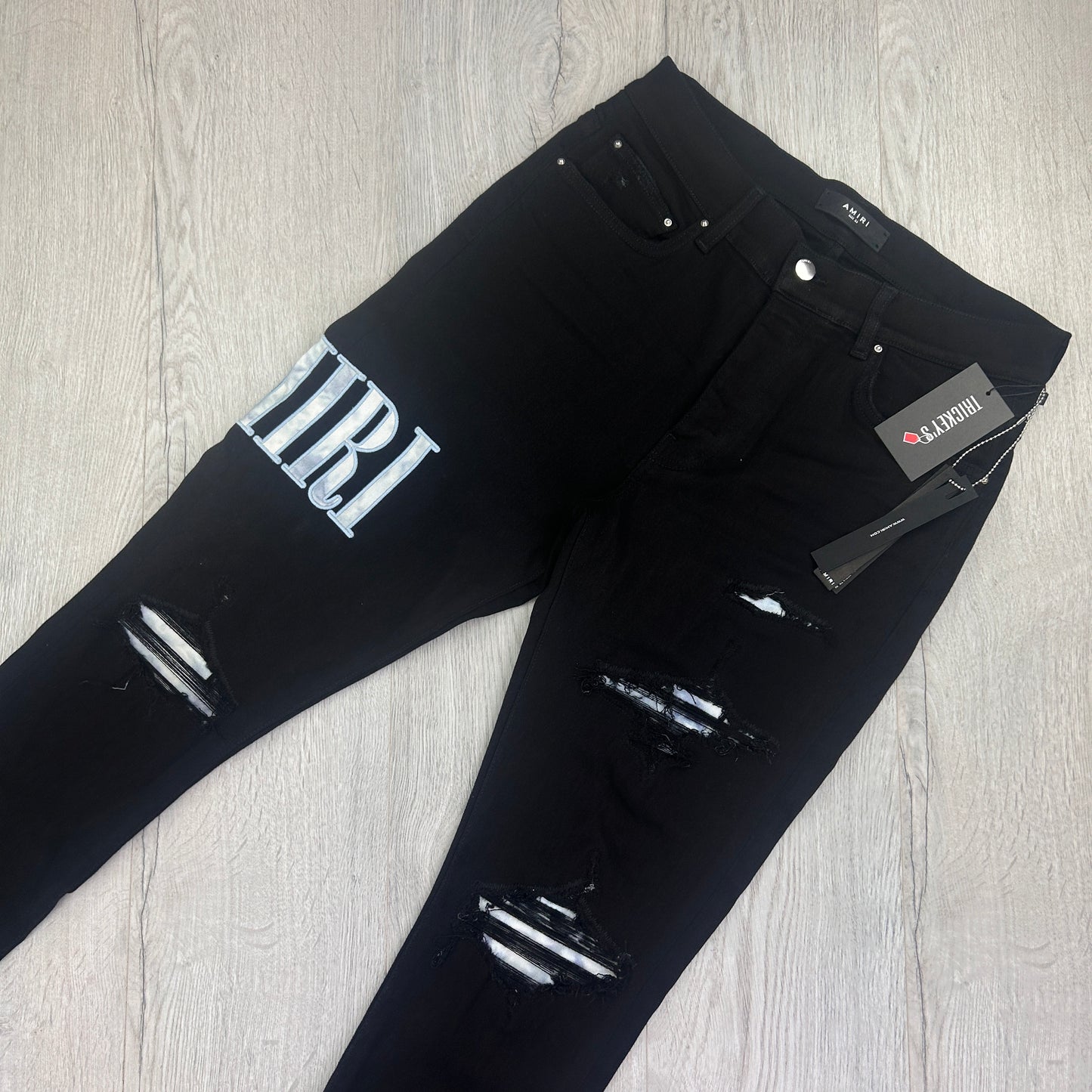 Amiri MX1 Men’s Black Distressed Jeans With Blue Side Logo