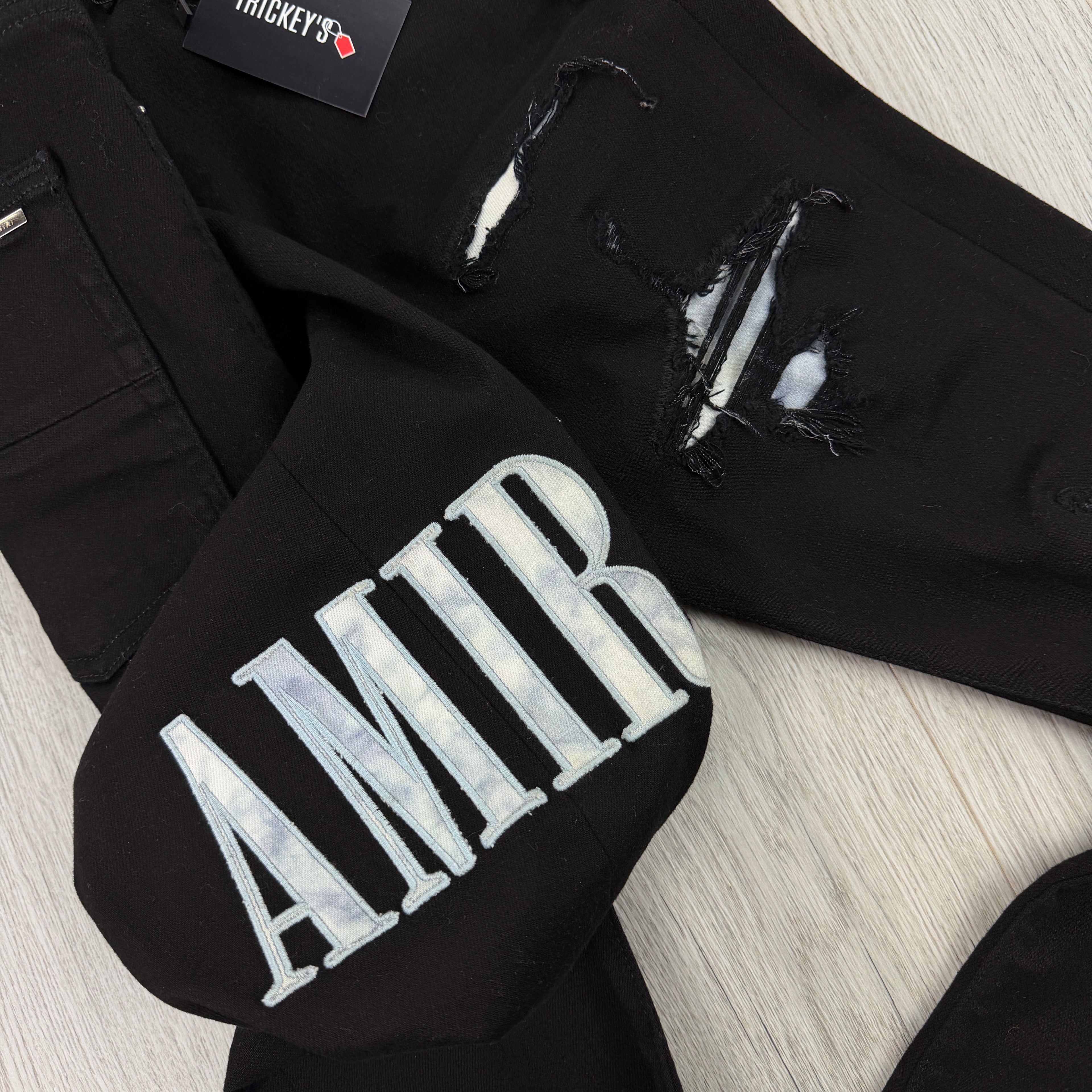 Amiri MX1 Men’s Black Distressed Jeans With Blue Side Logo
